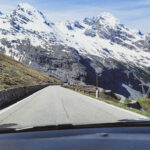 Mit dem Auto durch die Alpen: Atemberaubender Blick auf die italienischen Alpen aus dem Autofenster, der die Aufregung und Vorfreude der Radfahrer einfängt.