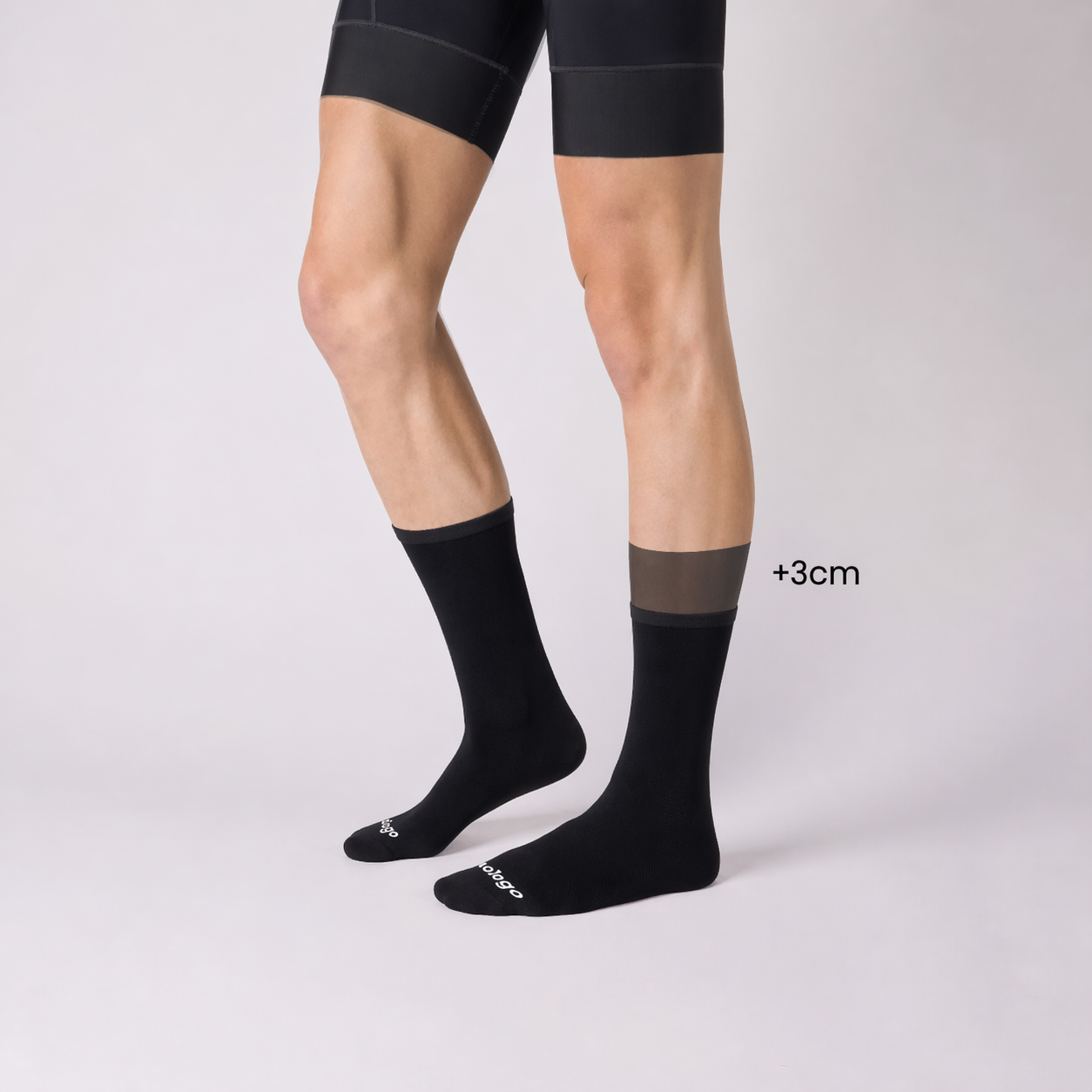 Side view of black nologo cycling socks with a visual +3 cm height comparison, showing the extended cuff length versus the standard version.